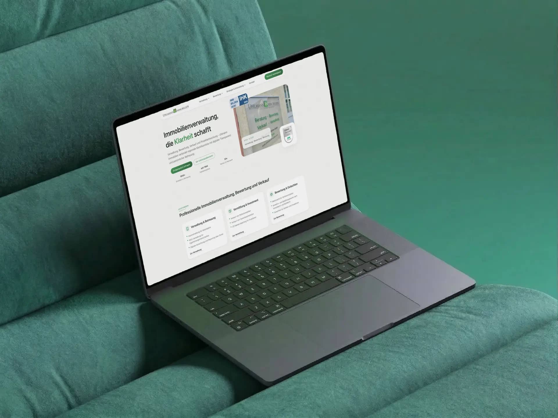 Startseite von Uhlmann Immobilien mit Leistungsübersicht auf einem Laptop auf grünem Samt