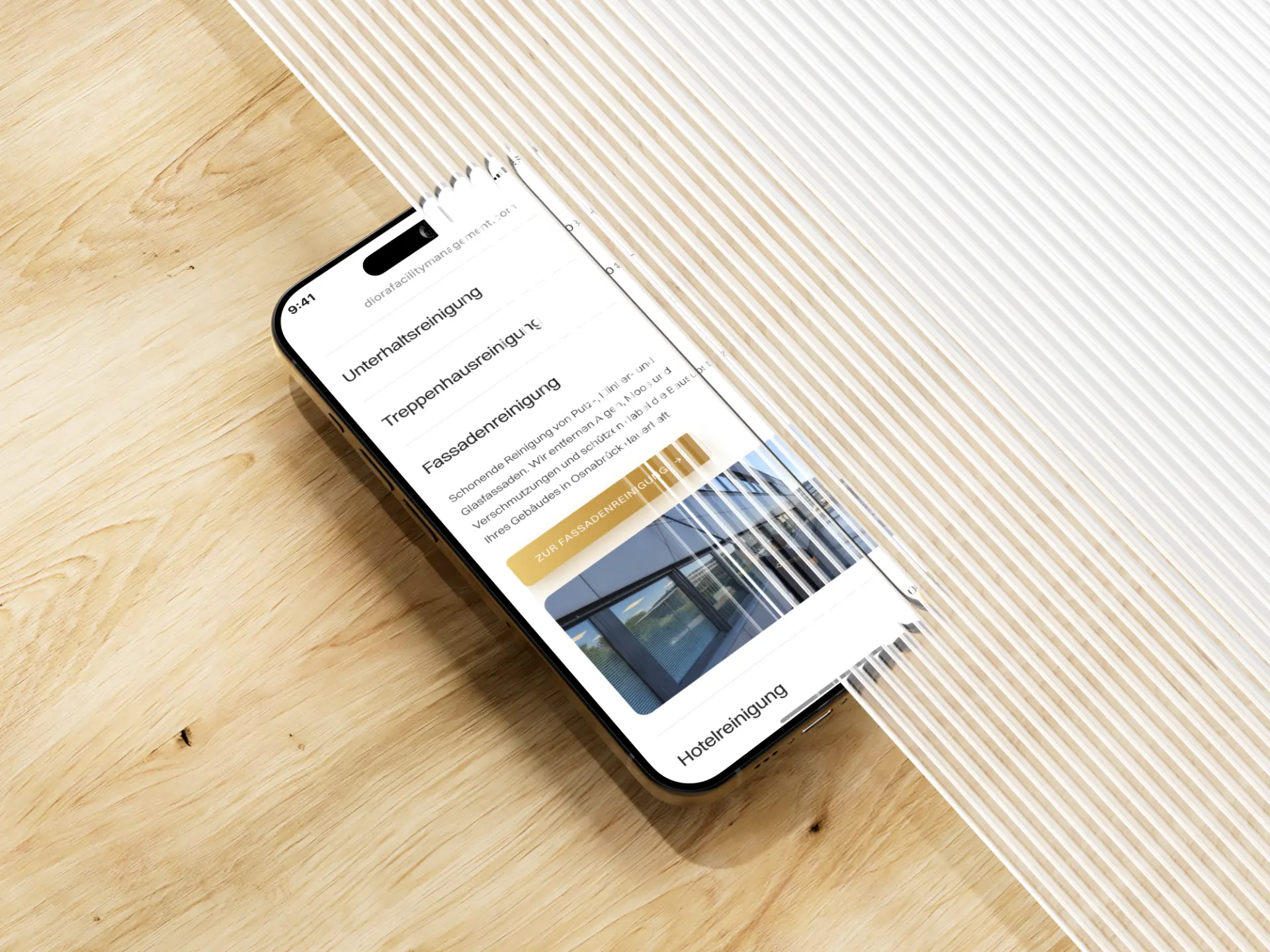 Leistungen von Diora Facility Management auf einem Smartphone auf Holz, bei der Fassadenreinigung aufgeklappt